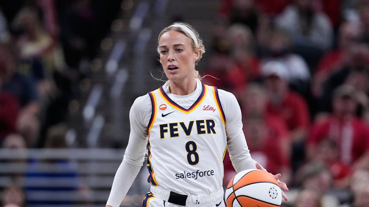 A basketball player in a white jersey dribbles a basketball.