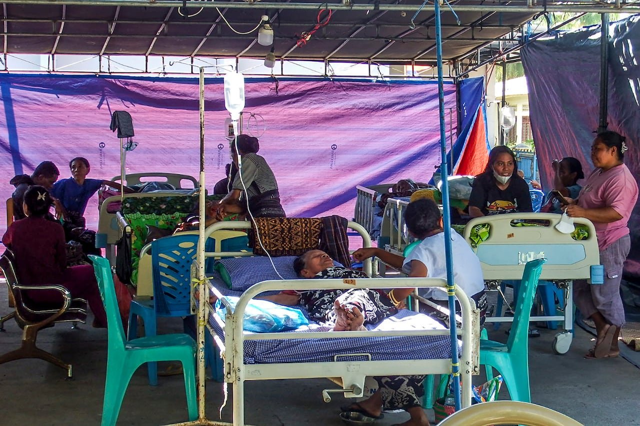 Several people under a tent, with some receiving medical aid.