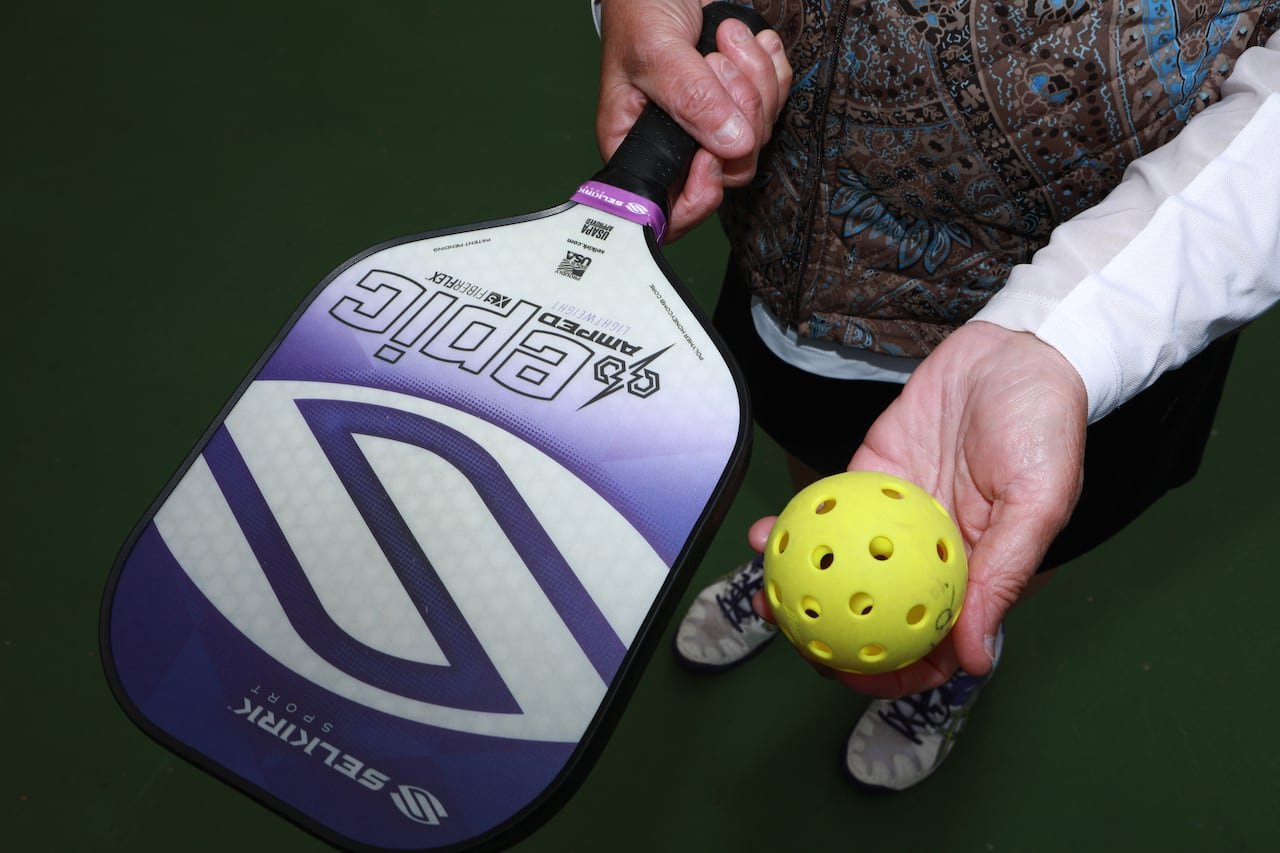 default-734 Close up photo of a pickleball paddle and ball in a woman's hands.